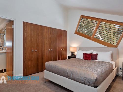 une chambre avec un grand lit et une fenêtre dans l'établissement The Peak Penthouse 8, à Thredbo