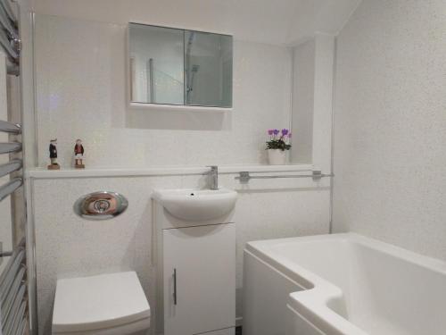 a bathroom with a sink and a toilet and a tub at ChiPad Duo - Comfy house with garden & parking in Chichester