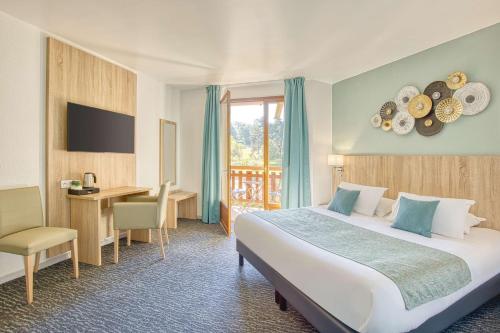 a hotel room with a large bed and a desk at Les Hameaux De Lozere Sure Hotel Collection by Best Western in Fournels