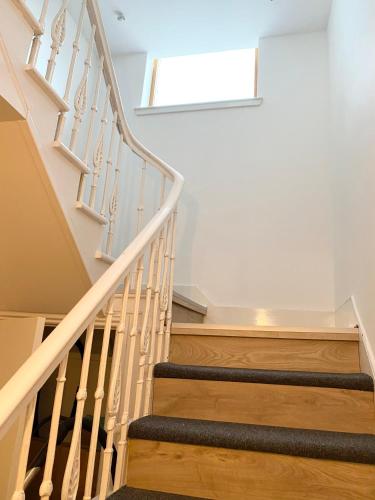 a winding staircase with wooden railings in a house at Waterloo Townhouse Inverness in Inverness