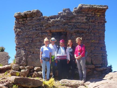 a group of people standing in front of a stone building at Taquile Hospedaje Mario in Huillanopampa