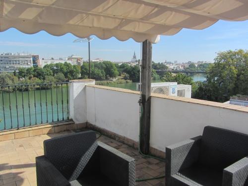balcón con 2 sillas y vistas al río en Trianabridgeviews Ático con vistas al puente de Triana calle Castilla 38, en Sevilla