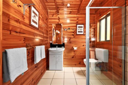 a bathroom with wooden walls and a toilet and a sink at Lumera Eco Chalets in Saint Marys