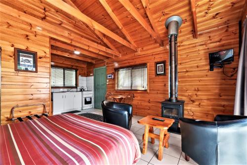a log cabin with a bed and a stove at Lumera Eco Chalets in Saint Marys