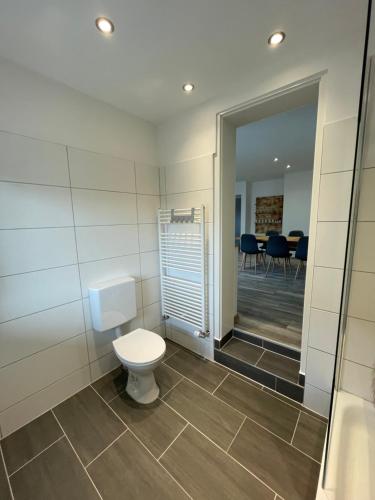a bathroom with a toilet and a room with chairs at Linus und seine Ferienwohnungen 2 in Heldrungen