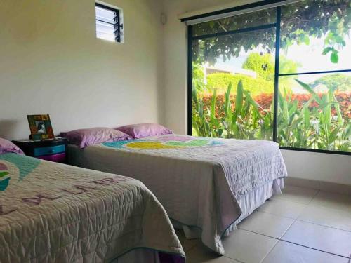 a bedroom with two beds and a large window at La Felicidad: el lugar ideal para el descanso in Carmen de Apicalá