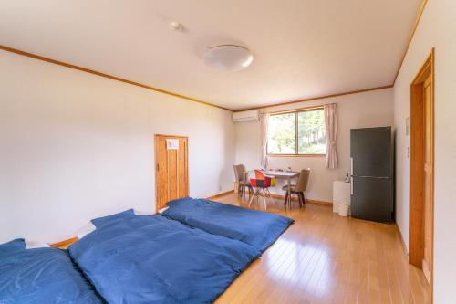 a bedroom with a bed with blue sheets and a table at Share Creative&Bed adonoan in Takeo