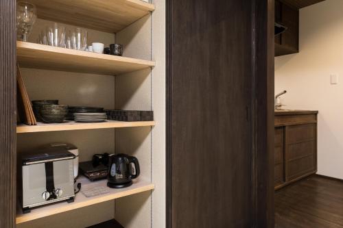 a kitchen with wooden shelves with a coffee maker at Kaga House in Kanazawa