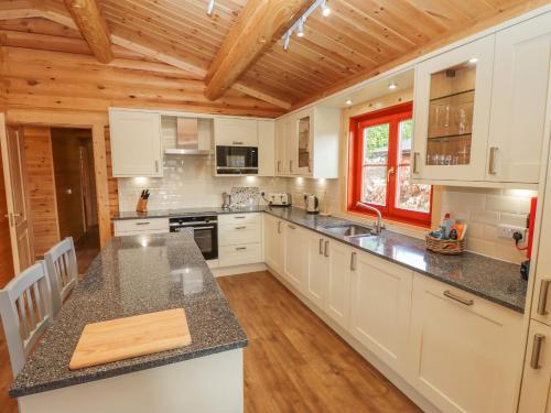 a kitchen with white cabinets and a wooden ceiling at Maple Lodge in Oakham
