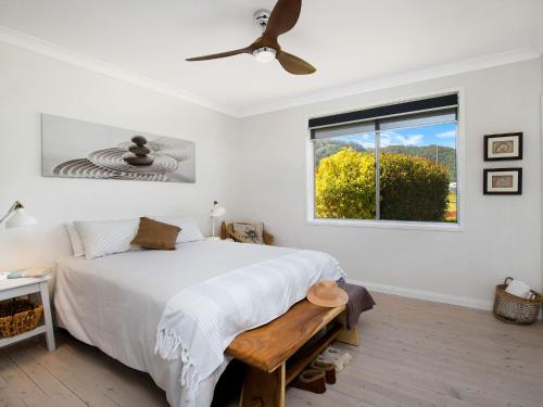 um quarto com uma cama, uma ventoinha de tecto e uma janela em Ocean Willow Gerringong em Gerringong