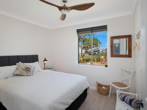 a white bedroom with a bed and a window at Ocean Willow Gerringong in Gerringong