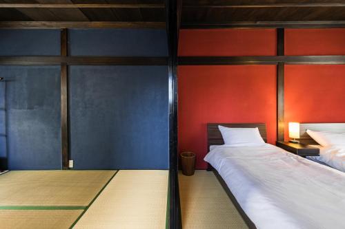 two beds in a room with red and blue walls at Kaga House in Kanazawa