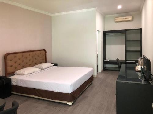a bedroom with a bed and a desk with a television at Hotel Sinar 3 in Sedati