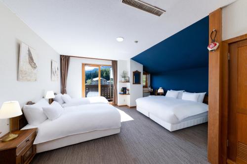 2 białe łóżka w pokoju z niebieską ścianą w obiekcie MARILLEN HOTEL by Hakuba Hotel Group w mieście Hakuba