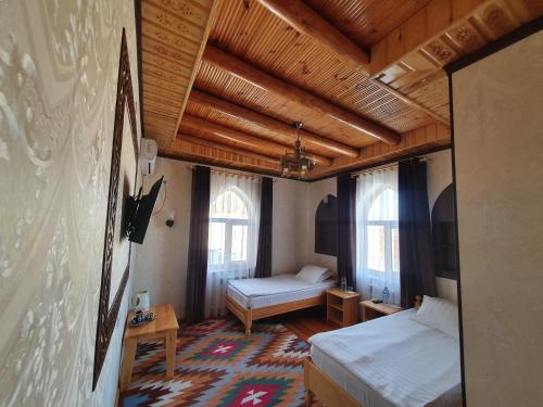 a bedroom with two beds in a room with wooden ceilings at Khiva Siyovush Hotel in Khiva