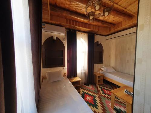 a bedroom with two beds and a table and a window at Khiva Siyovush Hotel in Khiva