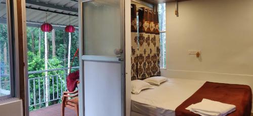 a small room with a bed and a window at The Inchara Hill View HomeStay in Chikmagalūr