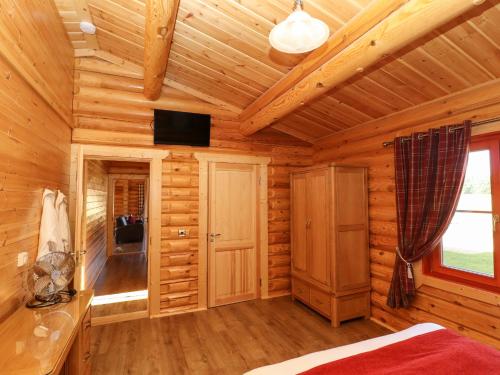 a bedroom in a log cabin with a bed and a television at Rowan Lodge in Oakham