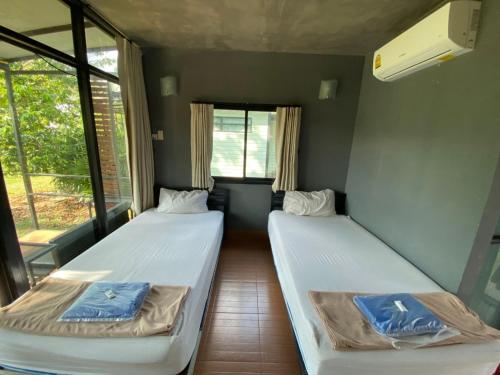two beds in a room with two windows at Baan Rim Nam Resort in Phangnga