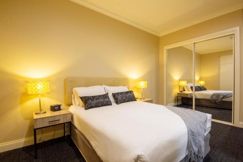 a bedroom with a large white bed and a mirror at Whyalla Playford Apartments in Whyalla