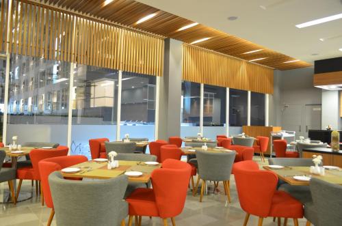 a restaurant with tables and chairs and windows at Kyriad Hotel Airport Jakarta in Tangerang