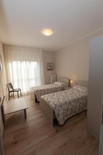 a hotel room with two beds and a chair at Rossini15 - garage privato in Alba