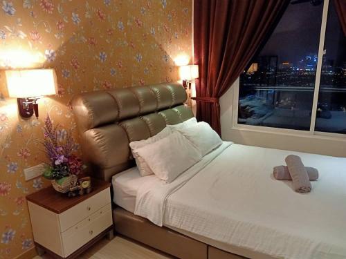 a bedroom with a bed with a leather headboard and a window at ExcluSuites Malacca @ The Wave Residence in Melaka