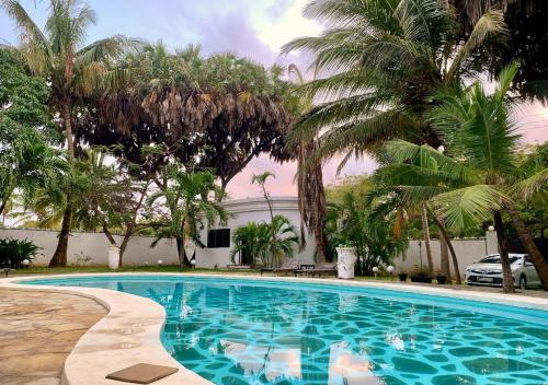 a swimming pool with palm trees and a building at Kenyan House Malindi in Malindi