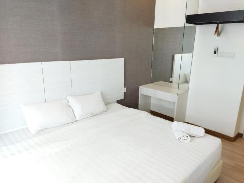 a white bed with two pillows and a mirror at ExcluSuites Malacca @ The Wave Residence in Melaka
