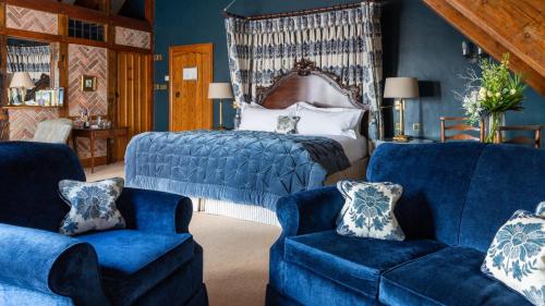 a bedroom with a bed and two blue chairs at Priory Wareham in Wareham