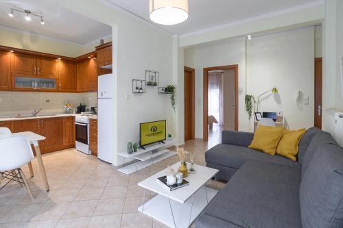 a living room with a gray couch and a kitchen at Yellow Fresh Apartment-City Center in Alexandroupoli