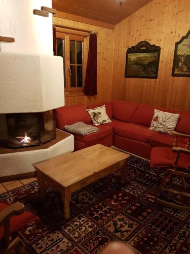 a living room with a red couch and a fireplace at Charming chalet with panoramic view and private parking in Gruyère in Gruyères