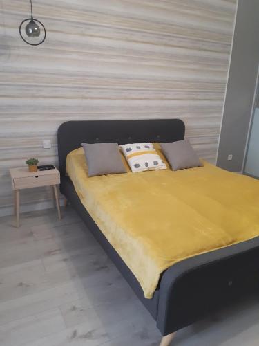 ein Bett mit einer gelben Decke und Kissen darauf in der Unterkunft Подолье in Winnyzja