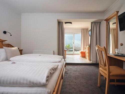 a hotel room with a bed and a desk with a desk at Hotel Garni Pinzgau, Fabian Hüttl in Neukirchen am Großvenediger