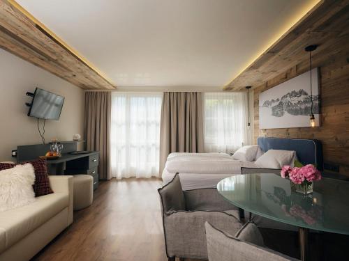 ein Wohnzimmer mit einem Sofa, einem Bett und einem Tisch in der Unterkunft Hotel Garni Pinzgau, Bernd Hüttl in Neukirchen am Großvenediger
