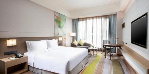a hotel room with a white bed and a flat screen tv at Holiday Inn Shunde by IHG in Shunde