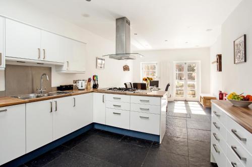 a white kitchen with white cabinets and a sink at Walsingham House Winchester in Winchester