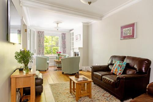 a living room with a leather couch and a table at Walsingham House Winchester in Winchester