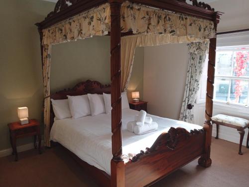 1 dormitorio con cama con dosel y almohadas blancas en Blue Bell Hotel, en Belford