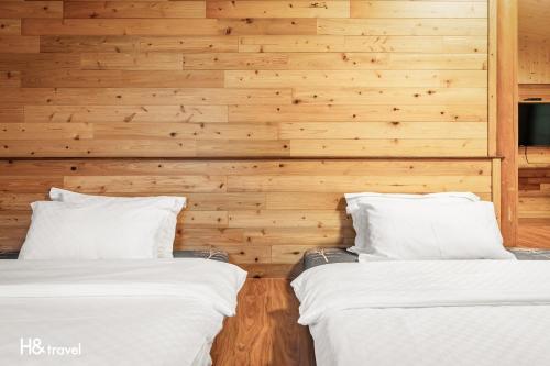two beds in a room with wooden walls at Alishan Sunrise B&B in Fanlu