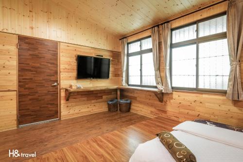 a room with a bed and a tv and windows at Alishan Sunrise B&B in Fanlu