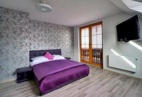 een slaapkamer met een paars bed en een flatscreen-tv bij Apartamenty EverySky - Prusa 2a-22 in Karpacz