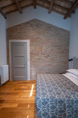a bedroom with a bed and a brick wall at Sei Sequoie Nature & Charme in Ravenna
