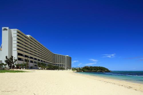 a building on the beach next to the ocean at Hotel Monterey Okinawa Spa & Resort in Onna