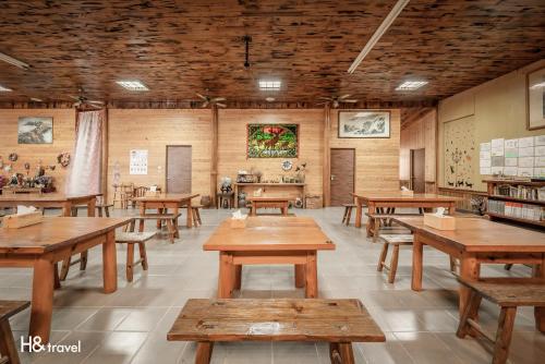 uma sala de aula com mesas de madeira e bancos numa sala em H& Alishan Sunrise B&B em Fanlu