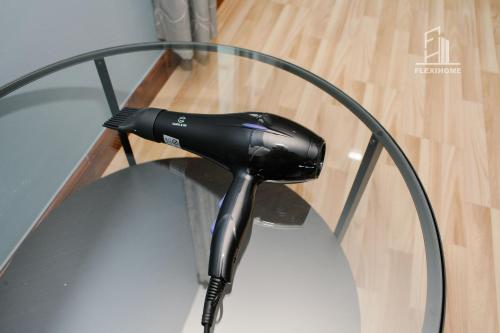 a black hair dryer sitting on top of a glass table at 10am-6pm, SAME DAY CHECK IN AND CHECK OUT, Work From Home, Shaftsbury-Cyberjaya, Comfy Home by Flexihome-MY in Cyberjaya