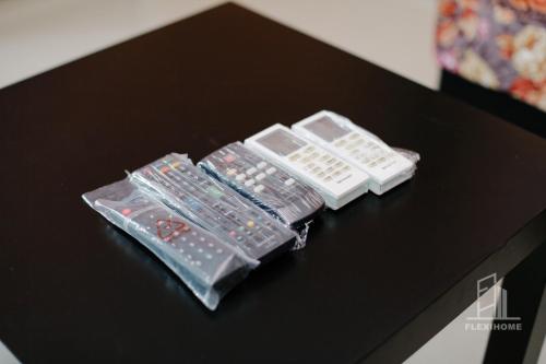 two remote controls sitting on top of a table at 10am-6pm, SAME DAY CHECK IN AND CHECK OUT, Work From Home, Shaftsbury-Cyberjaya, Comfy Home by Flexihome-MY in Cyberjaya
