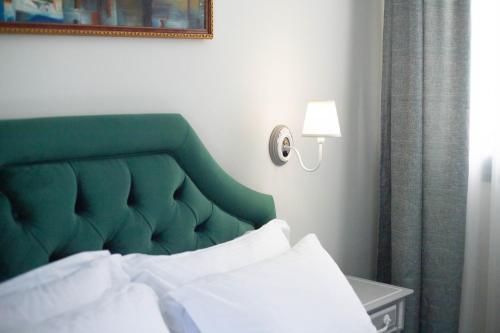 a bed with a green headboard in a room at Pandrosos Divine Suites in Athens