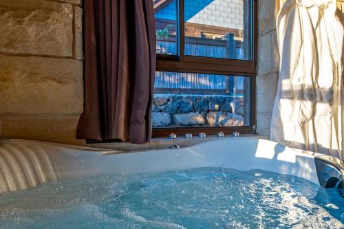 a bath tub in a bathroom with a window at Gilad Cabins in Odem