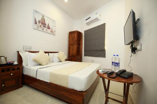 a bedroom with a bed and a table with a television at Hotel Casa by the lake in Udaipur